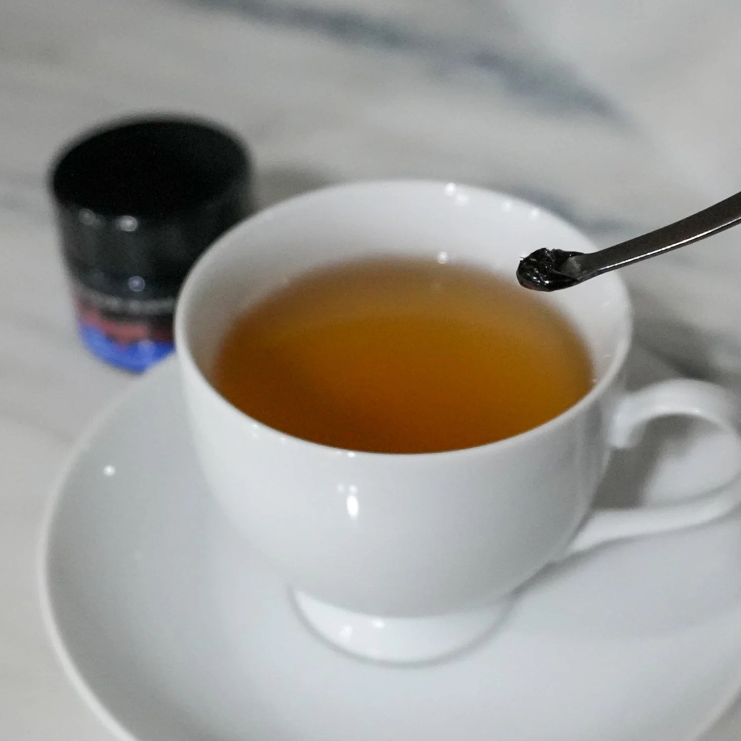 White cup of tea with a spoon on a white plate, blurred background