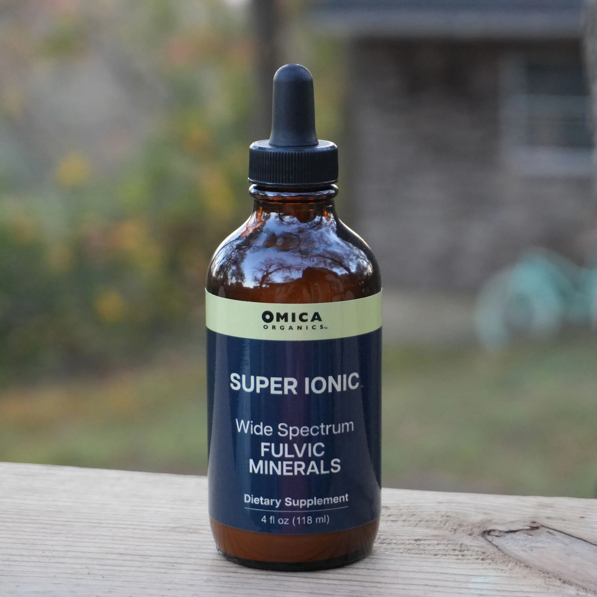 Bottle of Omica Organics Super Ionic Fulvic Minerals on a wooden surface with a blurred natural background